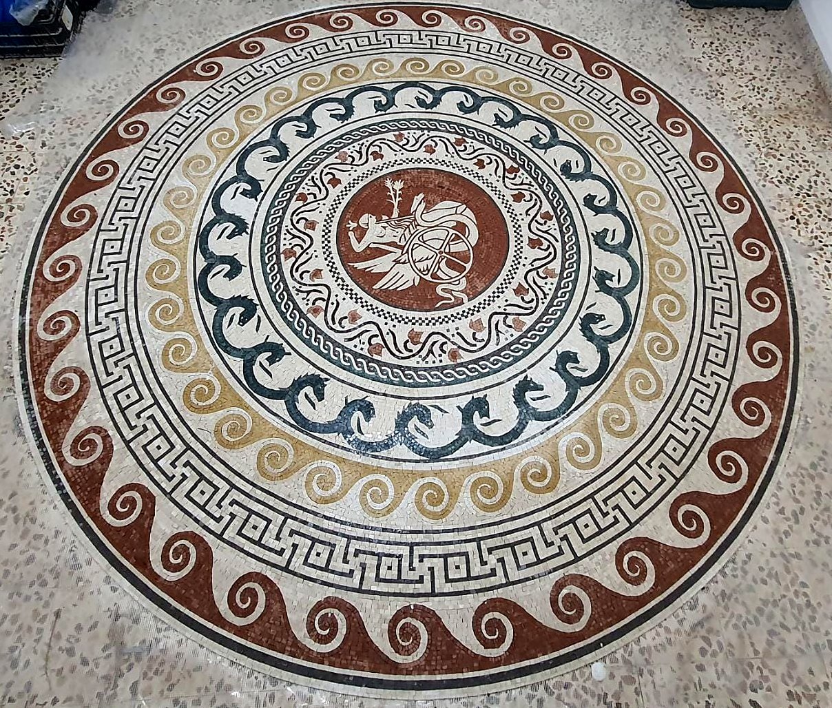 Round floor mosaic with wave, Greek key and sea-horse borders around a chariot medallion